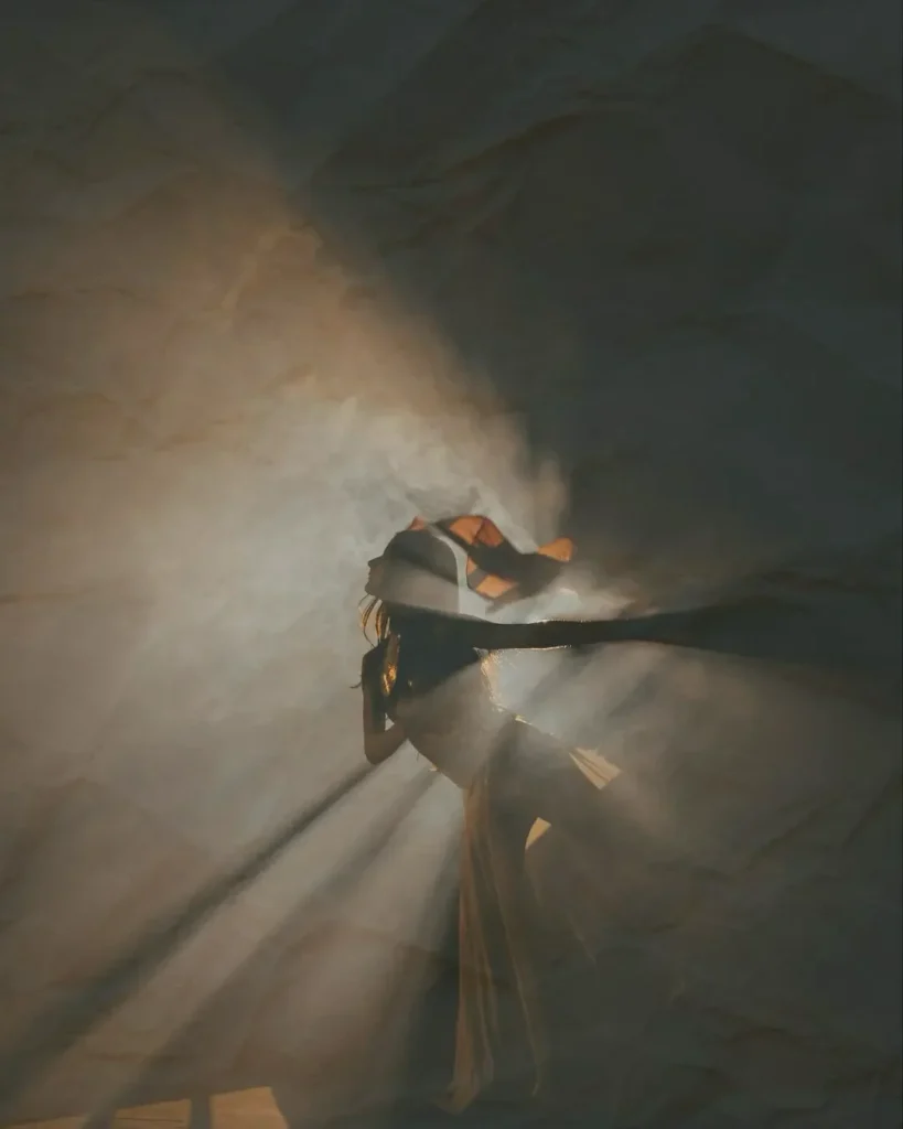 Woman dancing on a smoky, dark stage.