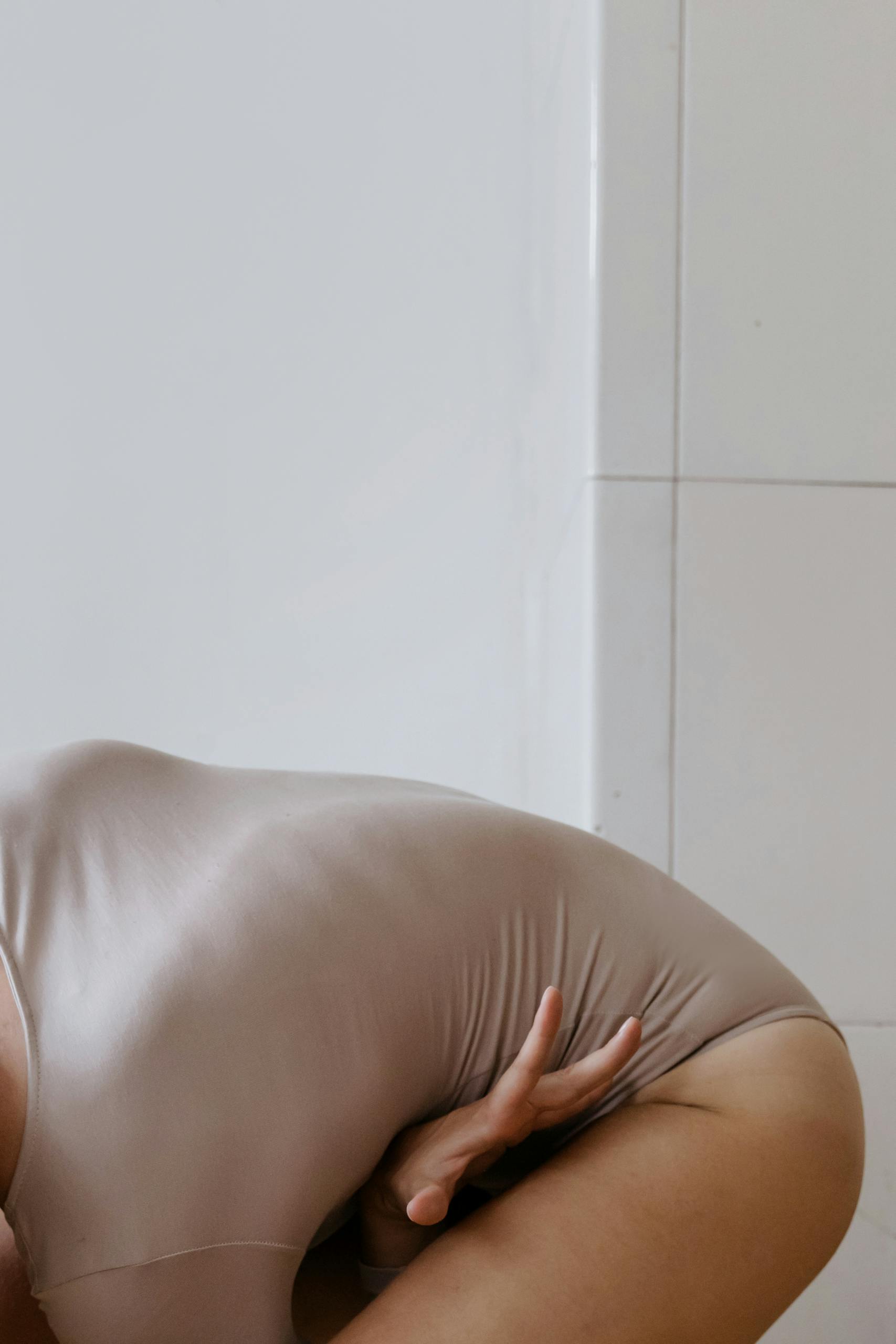 A focused yoga pose emphasizing flexibility and balance in a neutral setting.