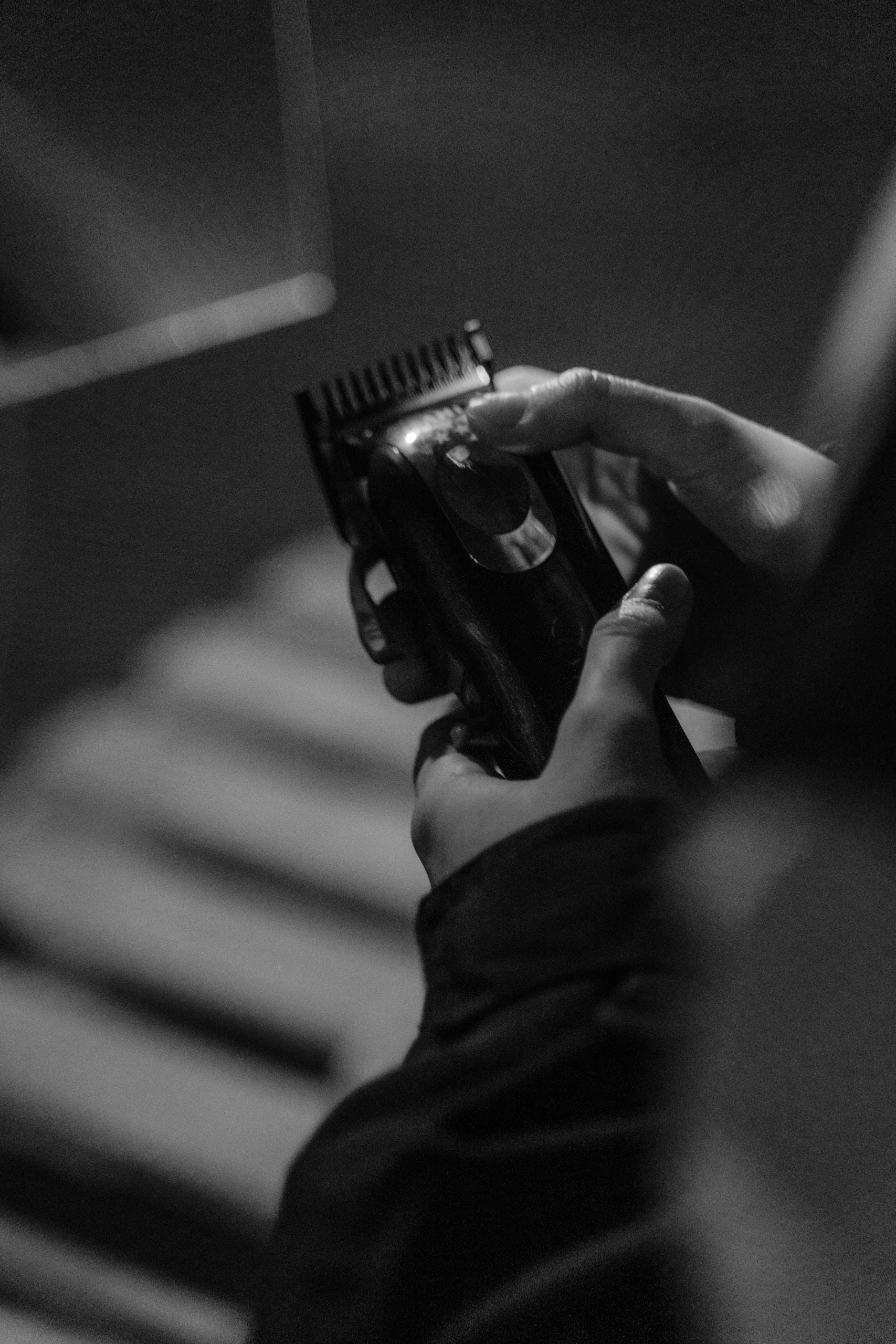 Black and white close-up of hands holding a hair clipper, showcasing personal grooming.