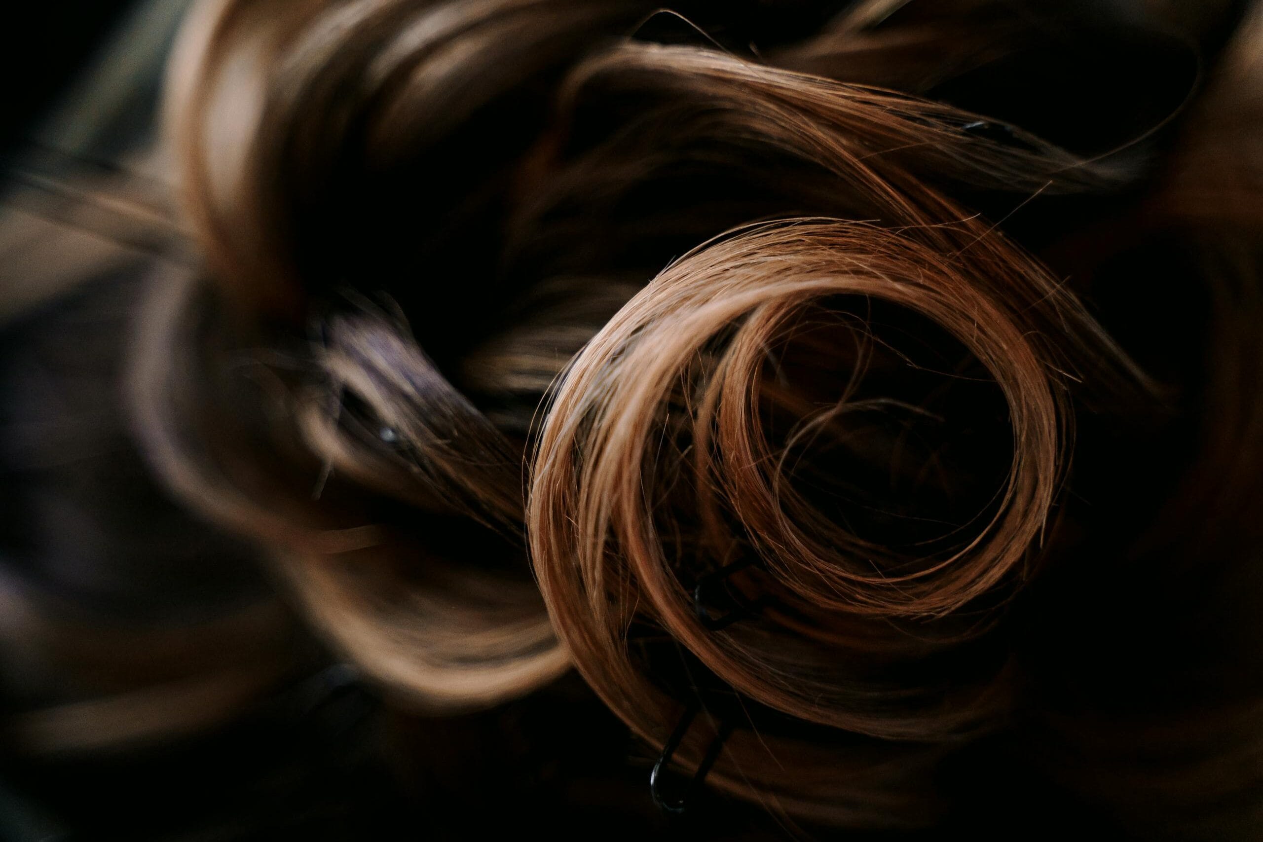 Closeup of crop unrecognizable female with pins in long wavy hair in daylight