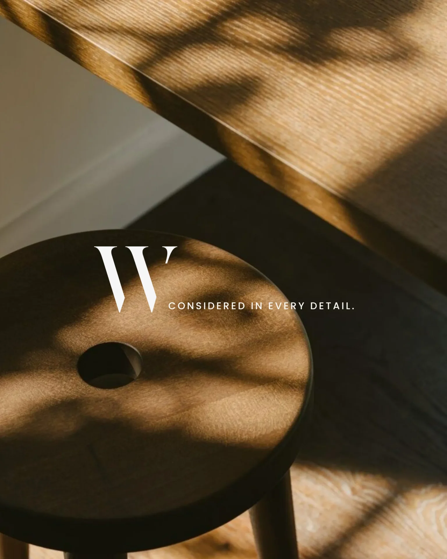 Close-up of a dark wooden chair seat with a large white logo and the words 'Considered in every detail' across it.