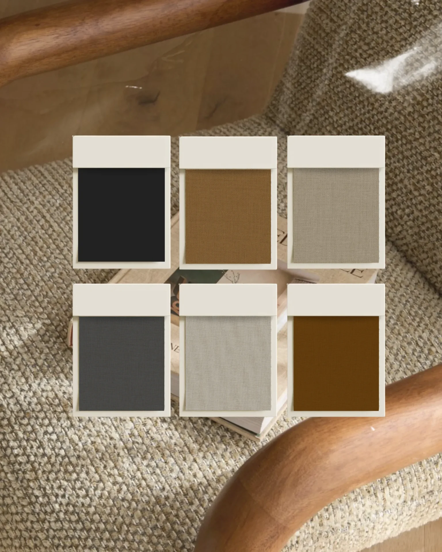 Display of six fabric swatches in white card holders arranged in a grid on a beige carpet, showing black, brown, tan, gray, and light beige textures for upholstery.